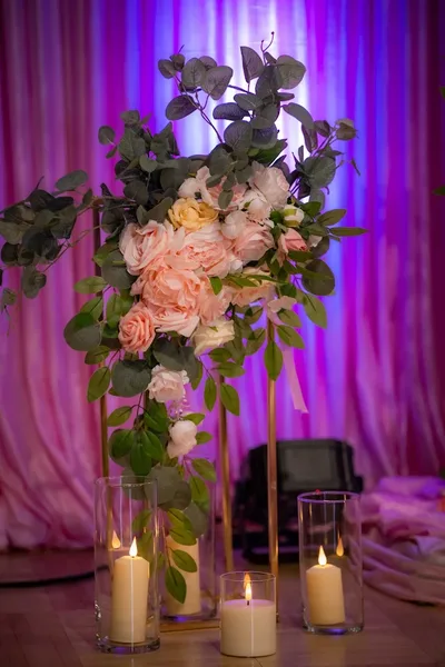 Floral centerpiece with candles under purple uplighting