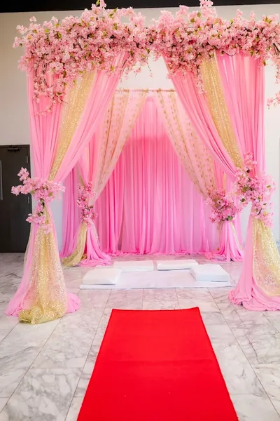Pink and gold ceremony arch with red carpet aisle on marble floors at MP Venue Event Center in DFW