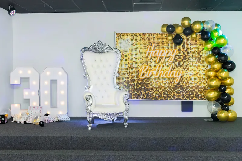 Wide view of ballroom with gold sequin backdrop and balloon arch