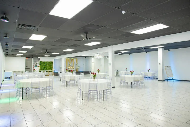 Ballroom rear view showing greenery wall, stage, and round tables at MP Venue