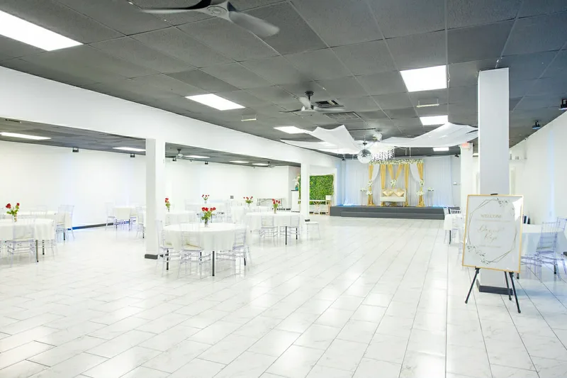 Spacious ballroom with white tables, gold stage backdrop, and welcome sign at MP Venue DFW