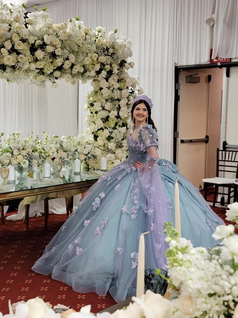 Quinceañera con vestido azul y fondo floral blanco en MP Venue DFW